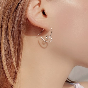 Close-up of heart-shaped 925 sterling silver earrings with textured spiral detail on ear