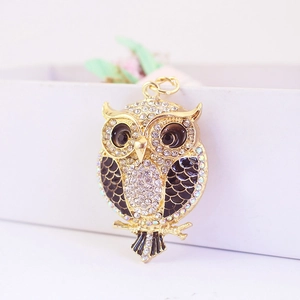 Golden owl keychain with sparkling rhinestones and black enamel detail on a gift box