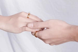 Close-up of a couple holding hands wearing gold wedding rings with a sparkling zircon diamond