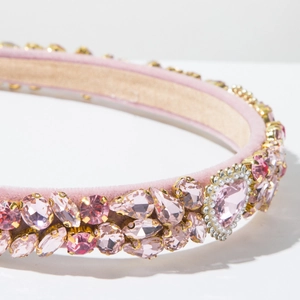Detailweergave van een roze hartkristal met witte parels op een fluwelen haarband