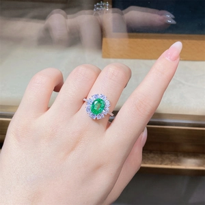 Macro detail of emerald ring with halo diamonds on a model's hand in a jewelry shop