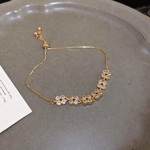 Detail of adjustable gold flower bracelet with zircon stones and sliding clasp closure