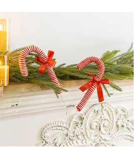 Detail view of red and white striped candy cane ornaments with bows on a festive mantel