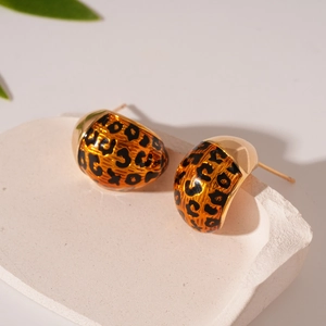 Close-up of leopard print teardrop earrings with gold plating on stone pedestal