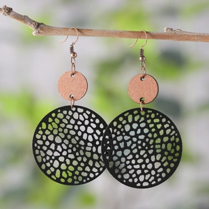 Detail of vintage geometric earrings with bronze upper disc and black cutout dangle discs