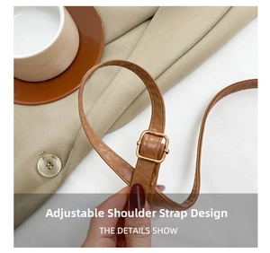 Detail of adjustable brown leather shoulder strap with gold metal buckle and stitching