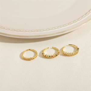 Three gold adjustable rings with multi-color zircon stones on a white textured background