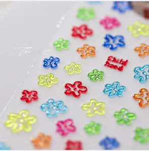 Macro shot of 3D floral nail art stickers with Child Hood text and colorful resin flower details
