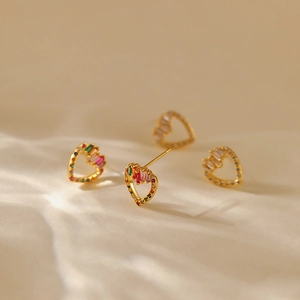 Macro detail of leaf-shaped earrings with colorful zircons and 18K gold plated finish
