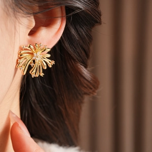 Gros plan de boucles d'oreilles fleurs dorées avec zircons étincelants sur l'oreille