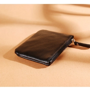 Detail of black lychee grain PU leather coin purse with zipper on textured background