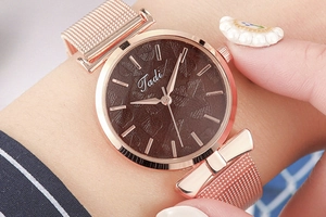 Détail de la montre à bracelet en maille or rose avec cadran à motif feuille et nœuds