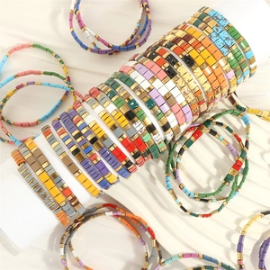 Macro shot of colorful Tila bead bracelets with gold square spacers on white stand