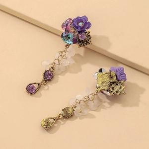 Macro detail of vintage floral earrings with iridescent crystal heart and purple gemstone