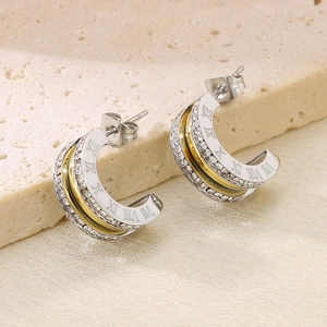 Detail view of heart earrings with Roman numerals and rhinestones on stone background