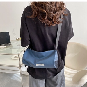 Vue détaillée du sac cylindrique bleu marine avec poche latérale en filet sur mannequin