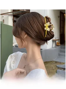 Detail shot of a yellow resin flower hair claw clip with golden metal tassels on a model