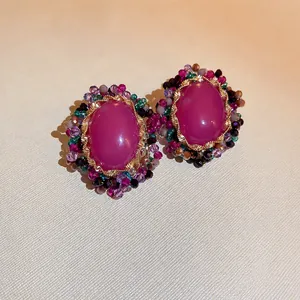 Vintage oval earrings with purple crystals and colorful beads on a gold frame