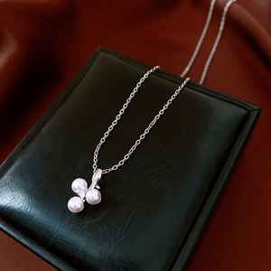 Close-up of stainless steel necklace with pearl cluster pendant and zircon on jewelry box