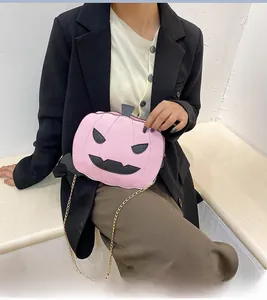 Detail of pink pumpkin-shaped bag with black leather eyes and black-gold chain strap