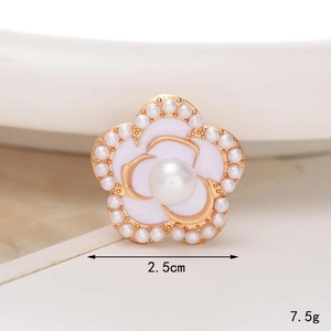Detailed close-up of a 2.5cm white enamel camellia flower charm with pearls and gold edging