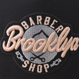 Flat brim baseball cap with Brooklyn Barber Shop embroidery on black twill fabric