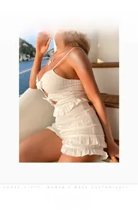 Detail of white two-piece set with bow-tie crop top and ruffled shorts on a yacht