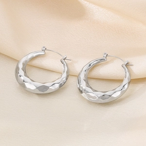 Detail of silver U-shaped earrings with hammered texture on champagne silk fabric