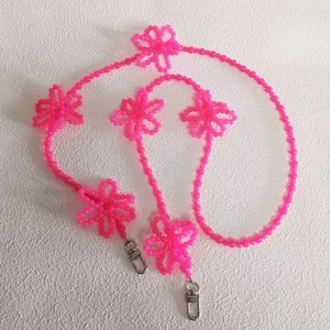 Detail of neon pink beaded crossbody chain with five flower charms and silver lobster clasps