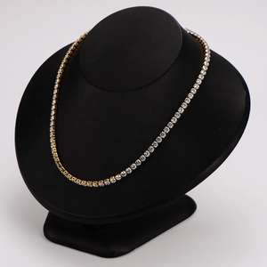 Elegant gold tennis necklace with clear cubic zirconia on a black mannequin display