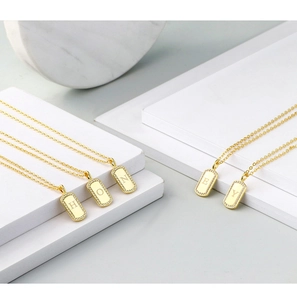 Detailed shot of gold letter necklaces with zircon stones on white marble blocks