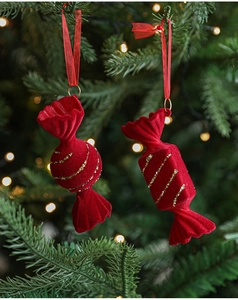 Close-up of red flocked Christmas candy ornaments hanging on a green Xmas tree branch