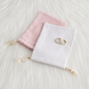 Detail of pink and beige cotton linen jewelry pouches with drawstring on plush background