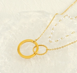 Detail of gold interlocking rings and small white pearls on a layered necklace