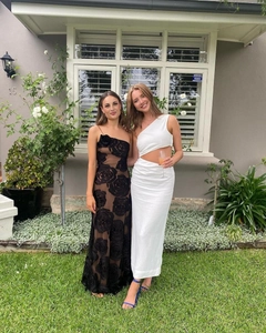 Detailed outdoor view of a black rose velvet mesh dress and white one-shoulder cutout gown