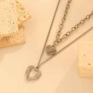 Detailed view of silver double-layered heart necklaces on decorative beige stones
