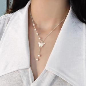 Elegant silver pearl necklace featuring a white butterfly pendant shown on a model