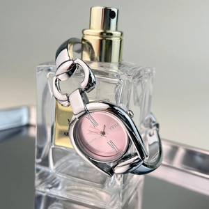 Detail of silver link bracelet quartz watch with pink dial on glass bottle