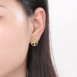 Close-up of a gold-colored stainless steel tree of life stud earring on a female ear
