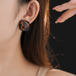 Gros plan de boucles d'oreilles carrées léopard avec bordure noire sur modèle