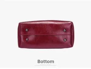 Detail of burgundy leather bag bottom featuring four protective metal feet and stitching