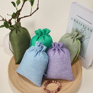 Linen drawstring bags in five colors displayed on a wooden tray with natural decor