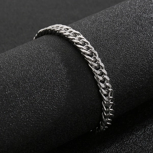 Macro view of silver Cuban chain link bracelet with OT clasp on black textured stand