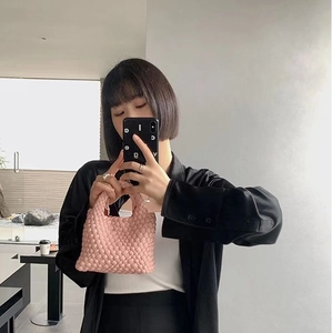 Pink woven mini bucket bag held by a model in a mirror selfie for daily outfit display