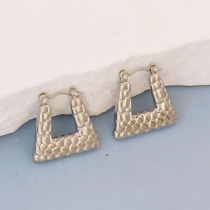 Macro shot of silver-tone irregular geometric trapezoid earrings with hammered texture
