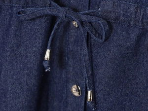 Detail of dark blue denim set showing metal buttons, drawstring, and fabric texture