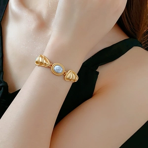 Detail of vintage gold bracelet with marble stone and shell design on model wrist