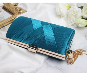 Detailed shot of peacock blue satin clutch bag with gold tassels and elegant pleats
