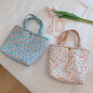 Close-up of floral cotton tote bags with metal snap buttons on quilted fabric