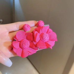 Close-up of pink fabric flower earrings with textured woven petals and silver needle